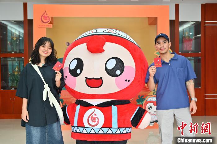 图为泰国留学生手持献血证与人偶合影。　俞靖 摄