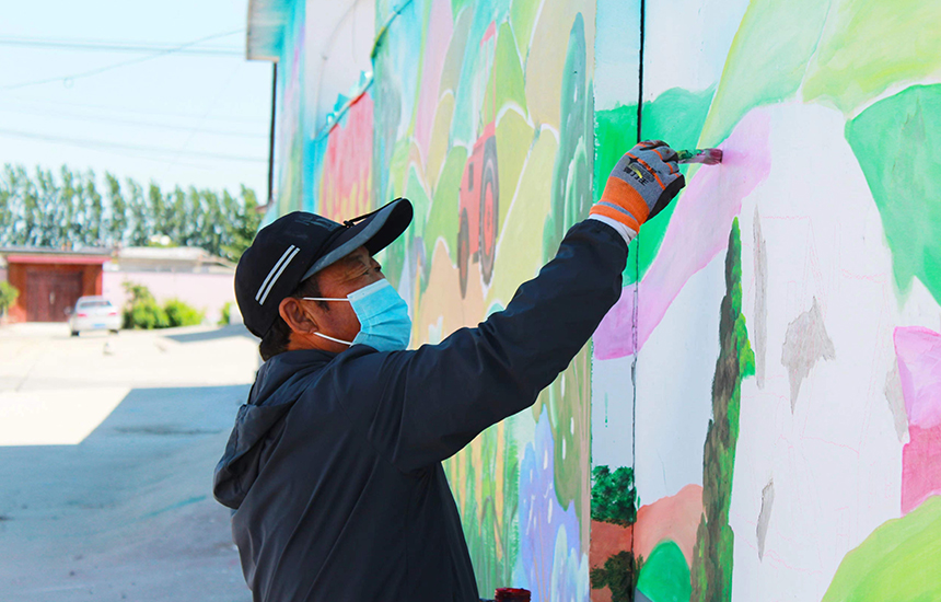 在河北省唐山市丰南区唐坊镇塘坊桥村，彩绘工人正在精心绘制乡村外墙。张杰摄