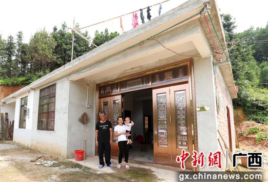 7月4日,在广西柳州市融安县大坡乡岗伟村,脱贫户肖裕安(左)与妻子、外孙在改造后的房屋前合影。覃庆和 摄