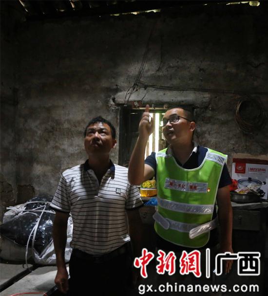 在融安县浮石镇谏村村洞口屯,第一书记黄亮(右)查看贫困户莫土全(左)的房屋情况。滕以洪 摄