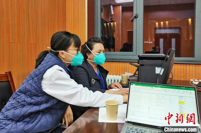 8月9日，杨苏乔(左)在拉萨方舱医院指挥部读取舱内患者胸部CT。　受访者供图