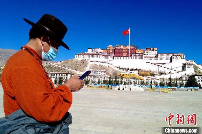 12月8日，西藏拉萨布达拉宫广场，来自四川甘孜的民众把刚刚拍摄的照片分享给亲朋好友。　李林　摄