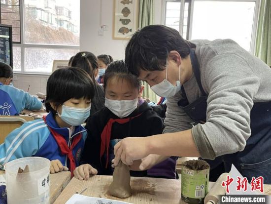 图为西宁市劳动路小学教师贾煜与学生一起制作陶艺。　周瑞辰子 摄