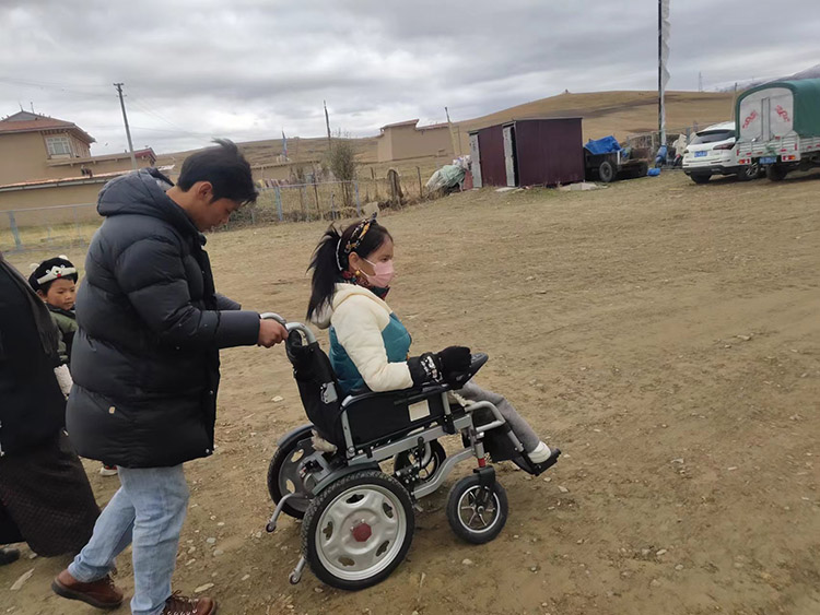 扎西夺尔登帮助村里的残疾小朋友。阿坝州文明办供图