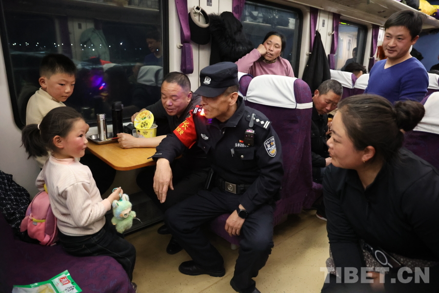 乘警长左红彬在巡视车厢间隙，向携带儿童的旅客专门叮嘱安全注意事项。.JPG