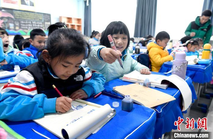 3月14日，西藏拉萨市第一小学一年级六班学生白玛朗珍(图左)在藏语文课上书写藏文。　李林 摄