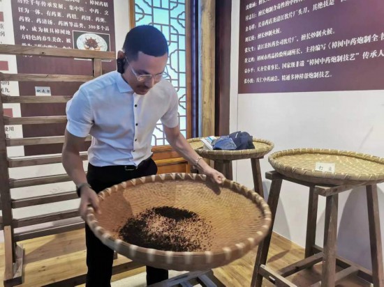 2023“一带一路”媒体合作论坛联合采访团团员在非遗文化展示馆体验中药炮制技艺。(本报记者 黄超摄)