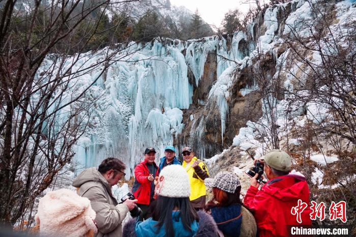 游客在晶莹剔透的冰瀑前拍照留念。　胡宇 摄