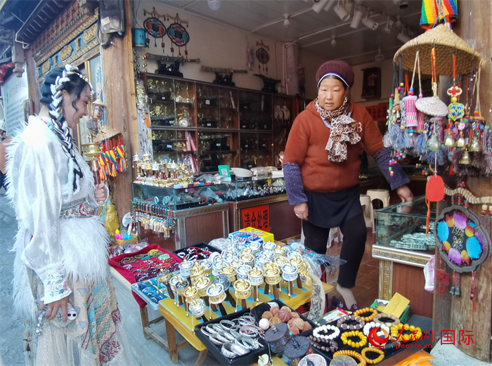 身着民族服饰的游客在独克宗古城店铺前察看商品。人民网记者 杜明明摄