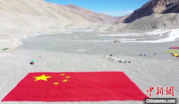图为在海拔5200多米的珠峰登山大本营展示的巨幅国旗。　视频截图