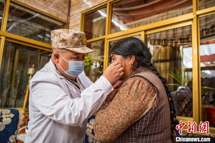 图为在西藏阿里地区札达县拓林镇，驻地部队军医为老人检查眼部情况。　刘晓东 摄