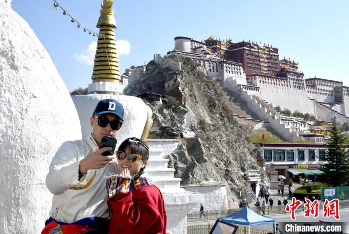 4月17日，游客身着藏式元素服装在拉萨布达拉宫观景台拍照留念。　李林 摄