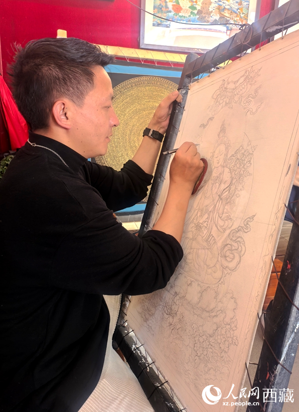 在八廓古城的一家唐卡体验馆内，一位画师正手持画笔，在画布上细细勾勒线条。人民网记者 吴雨仁摄