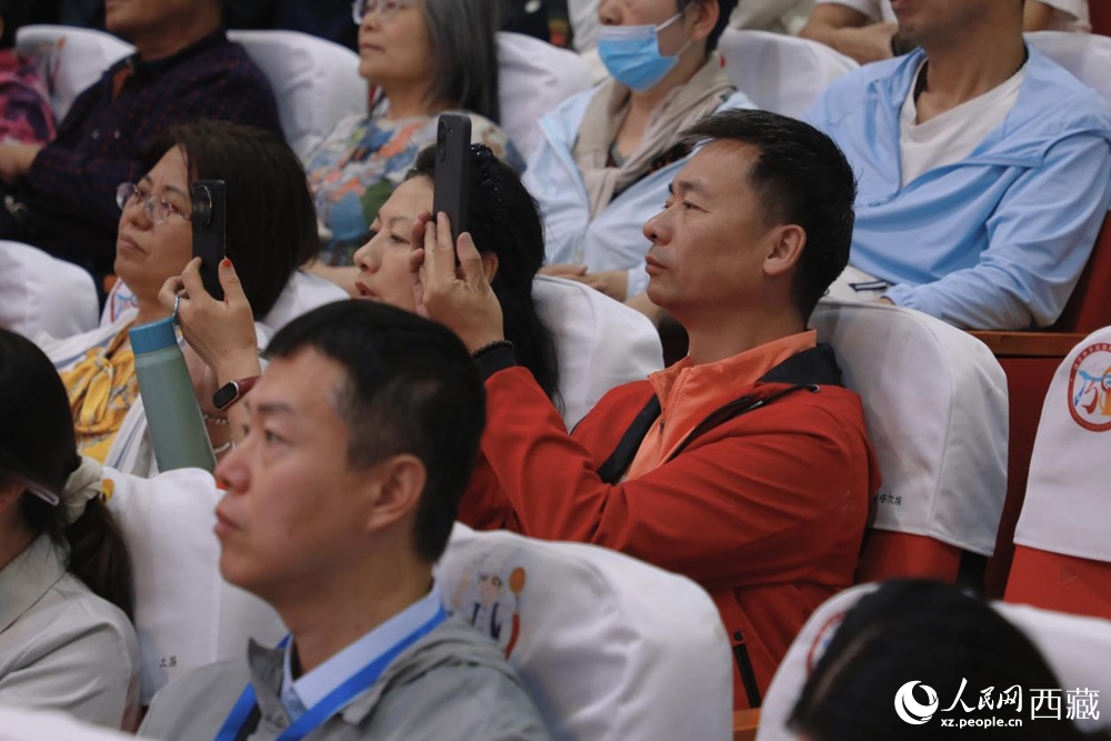 图为游客用手机记录精彩表演，沉浸于浓郁的文化体验中。人民网记者 次仁罗布摄