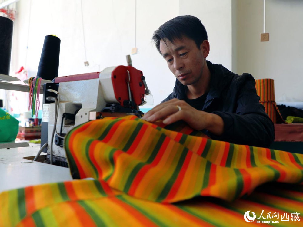 图为工人操作机器编织氆氇。人民网记者 次仁罗布摄