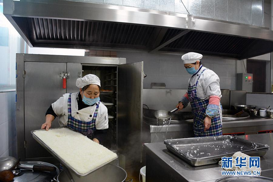 1月3日，重庆南川区北固中学食堂工作人员正在做饭炒菜。近年来，重庆南川区投入750余万元，为19所食堂装备蒸饭柜、冰柜等厨房设备6219台（套）。新华网赵紫东 摄