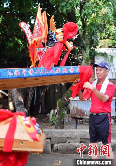 图为5月29日，长乐江田镇村民为即将入水的新龙舟系红布。　张斌 摄