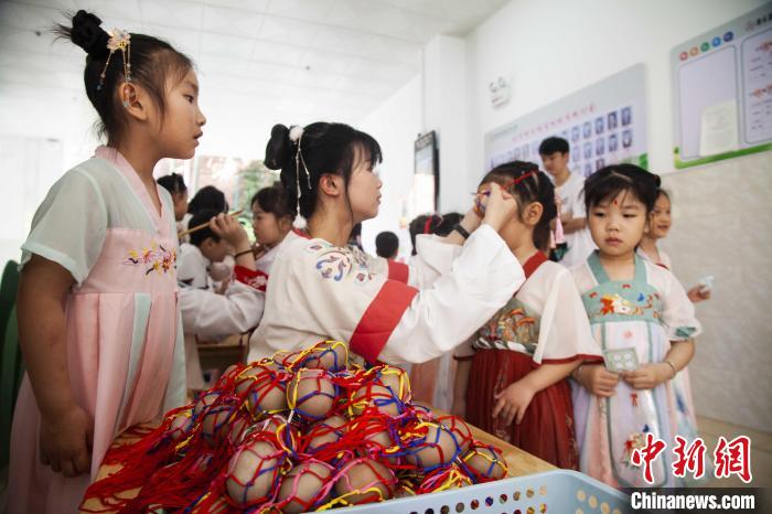 图为幼儿园的老师们穿上汉服为小朋友们戴上彩蛋，寓意着幸福安康。　董观生 摄