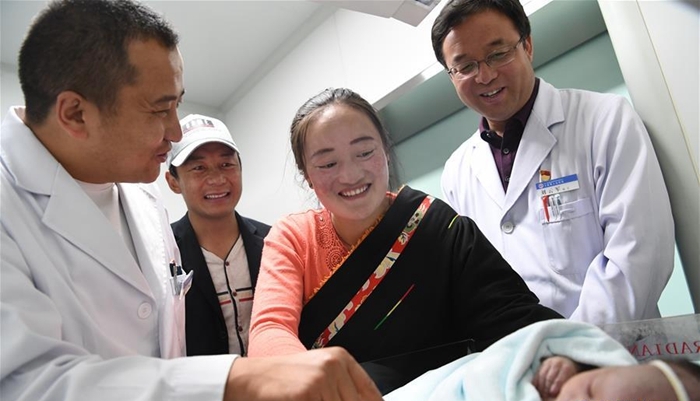 这是来自北京的援青干部刘云军（右一）看望新生儿（资料照片）。新华社发.jpg